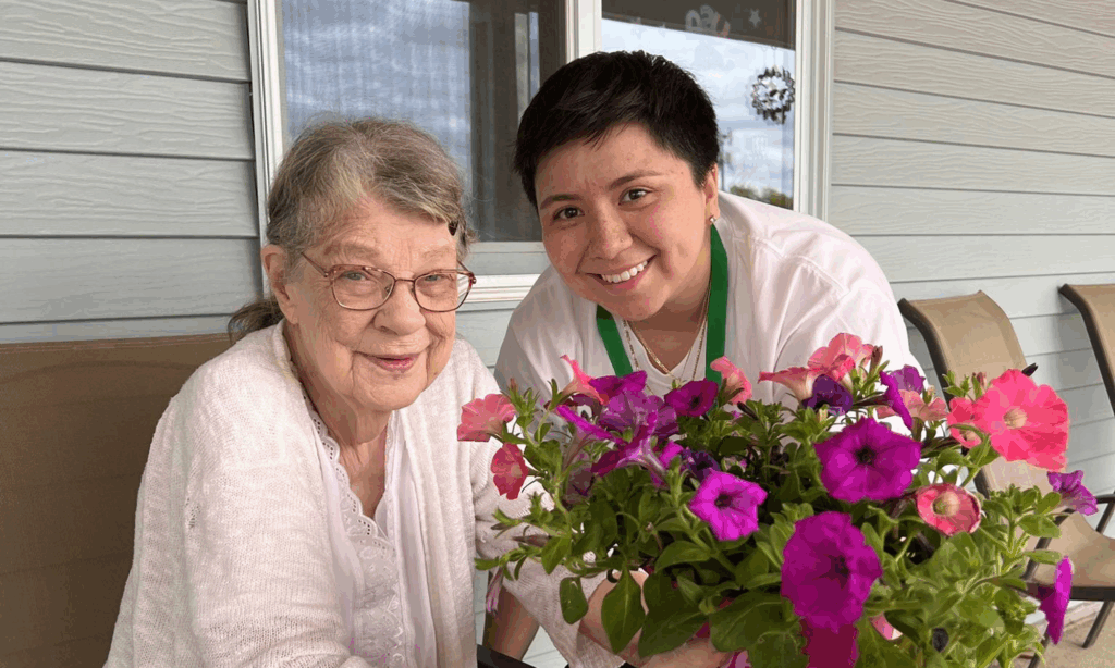 Senior female pictured holding a flower pot next to a hospice volunteer