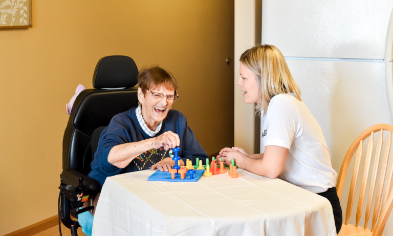 Wanda laughing with caregiver in a warm home setting, showing trust, comfort, and compassionate senior care.